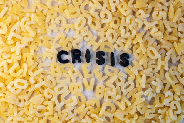 Foto crisis woord met alfabet letters soep pasta economische crisis en armoede concept