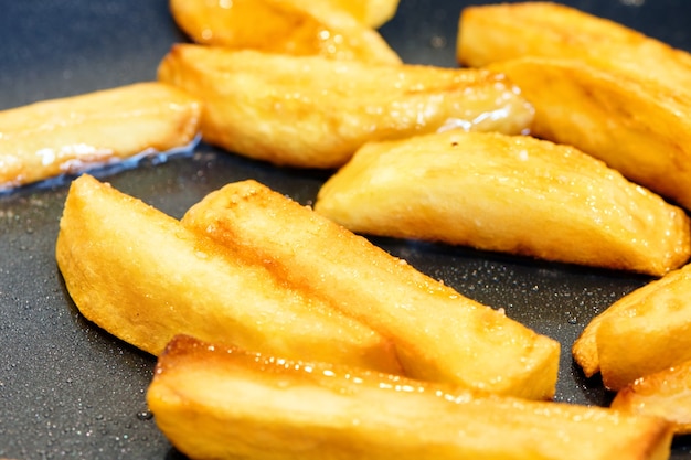 Crisp and golden french fries. Home made deep fried chips. Frying potato on pan. Food cooking background. Close up view with selective focus.