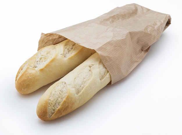 Crisp loaves of freshly made white bread in a paper bag. Isolated.