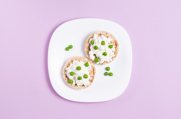 흰색 접시에 코티지 치즈와 녹색 완두콩 Crispbreads