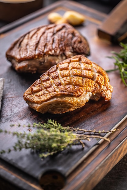 Foto petto d'anatra al forno croccante su un tagliere con erbe aromatiche di rosmarino e timo