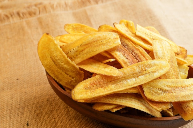 Crispy Banana Chips In Wooden Bowl On Burlap Sack Fabric