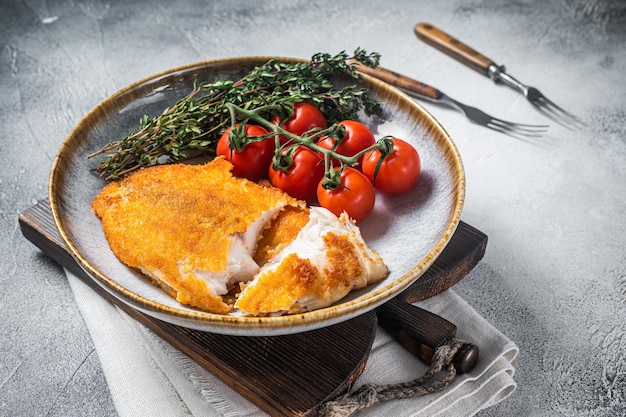 Crispy breaded tilapia filles on a plate with vegetables White background Top view