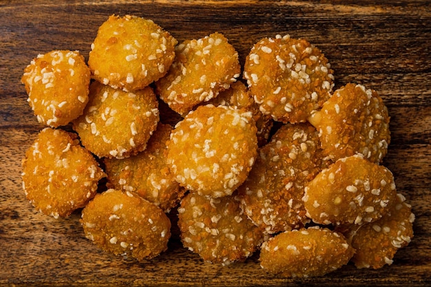 Crispy cheese nuggets served on wooden board on dark wooden backdrop closeup shot
