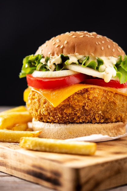 Crispy chicken burger with cheese and french fries on wooden table