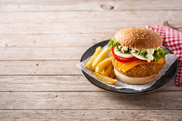 Crispy chicken burger with cheese on wooden table