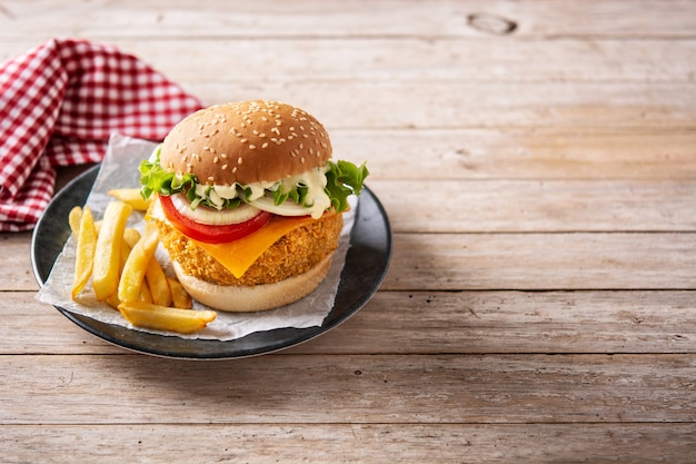 Crispy chicken burger with cheese on wooden table