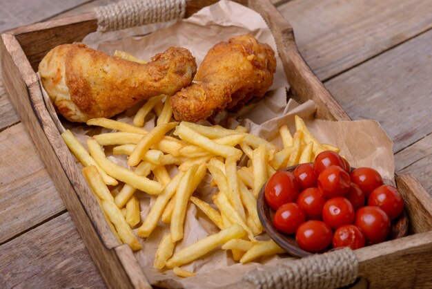 Foto cosce di pollo croccanti e patatine fritte con pomodori