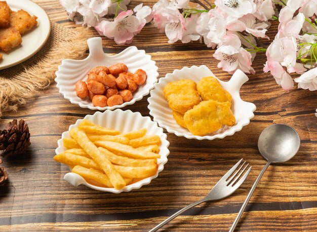 Crispy chicken nuggets with fried small bean crispy potato\
fries in dish side view on wooden table taiwan style food