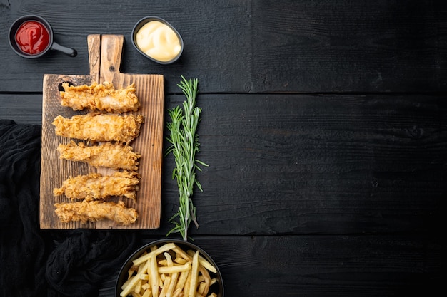 Crispy chicken sticks meat on black wooden table, flat lay,.