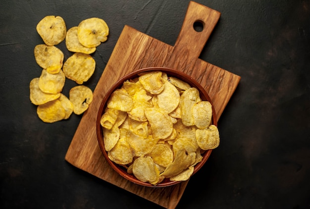 Crispy chips in a bowl on a stone background