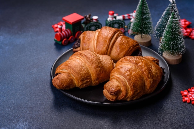 Crispy chocolate croissant with Christmas decorations on wooden cutting board