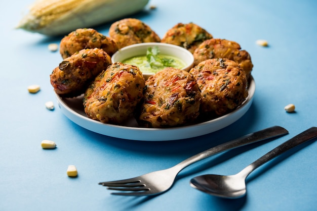 파삭 파삭 한 옥수수 Tikki, pakora 또는 pakoda 또는 커틀릿이라고도 알려진 패티. 녹색 처트니와 함께 제공됩니다. 선택적 초점