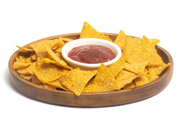 Crispy corn tortilla nachos chips with sauce in a wooden plate isolated on white background