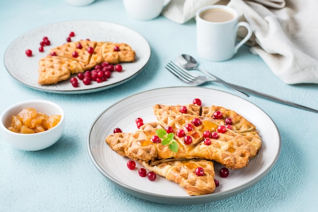 Crocchette croccanti con ribes rosso, miele e menta sui piatti, una tazza di caffè e marmellata su un tavolo luminoso. dolce deliziosa colazione