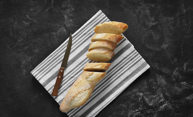 사진 어두운 탁자 위에 있는 린넨 냅킨에 바삭하고 신선한 얇게 썬 바게트