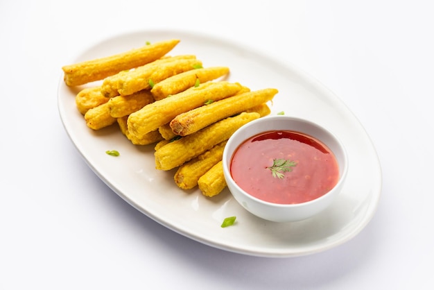 Crispy fried baby corn pakoda pakora or Baby corn fritters served with ketchup Indian food