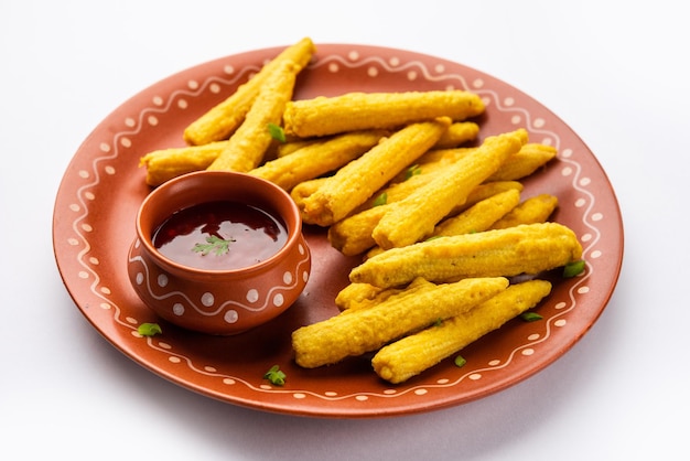 Crispy fried baby corn pakoda pakora or baby corn fritters served with ketchup indian food