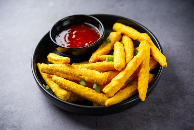 Photo crispy fried baby corn pakoda pakora or baby corn fritters served with ketchup indian food