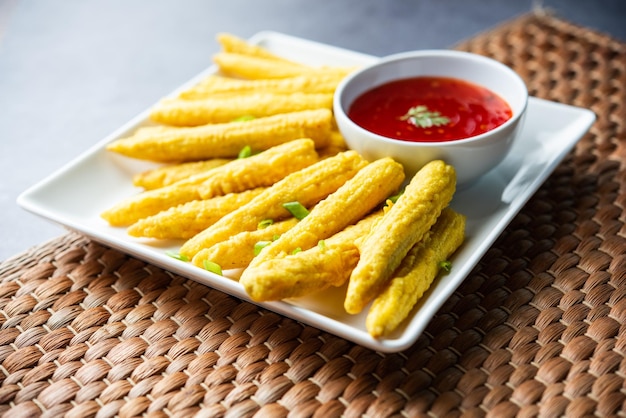 Crispy fried baby corn pakoda pakora or Baby corn fritters served with ketchup Indian food