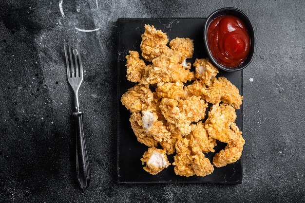 Crispy Fried breadcrumb covered chicken popcorn with ketchup Black background Top view