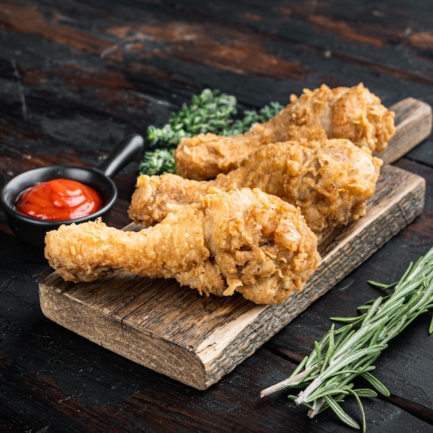 Crispy fried chicken drumstick on dark wooden table.