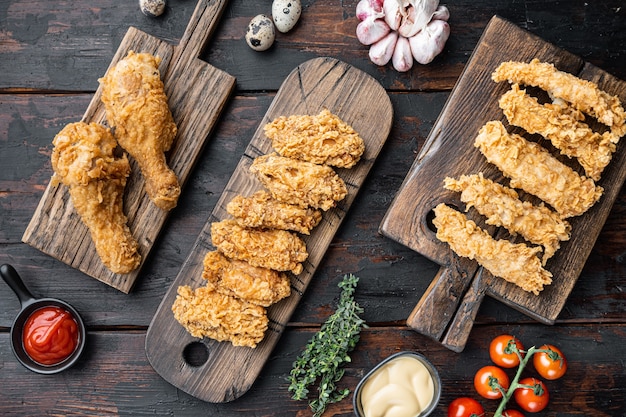 Crispy fried chicken parts on old dark wooden table, flat lay.