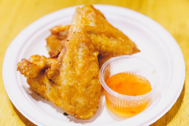 Crispy fried chicken wings with sauce placed in white plate blurred background