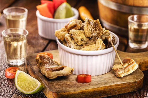 Crispy fried pork rinds or bacon served with cachaca or pinga typical food from Minas Gerais