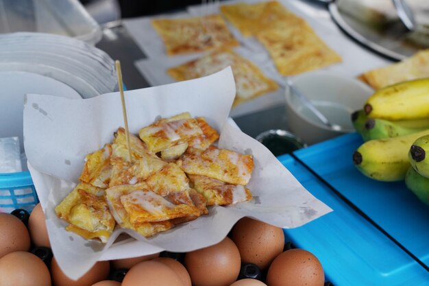 Хрустящая жареная роти с сахаром и сладким сгущенным молоком на бумаге