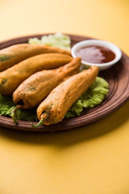 Pakora o mirchi bajji di peperoncino verde croccante, servito con ketchup su sfondo lunatico. è un popolare spuntino per l'ora del tè dall'india, specialmente nei monsoni. messa a fuoco selettiva