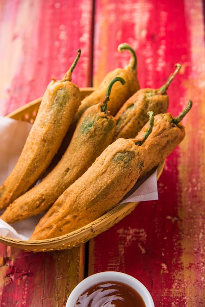 Crispy green chilli pakora or mirchi bajji, served with tomato ketchup over moody background. its a popular tea time snack from india especially in monsoon. selective focus