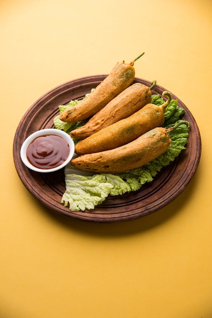 Crispy green chilli pakora of mirchi bajji, geserveerd met tomatenketchup op een humeurige achtergrond. het is een populaire theetijdsnack uit india, vooral in monsoon. selectieve focus