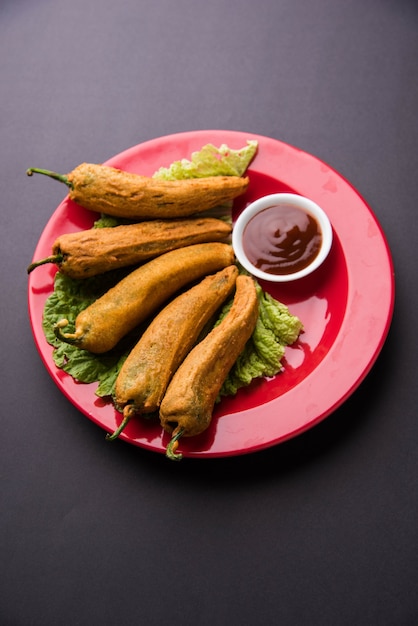 Crispy Green Chilli Pakora of Mirchi Bajji, geserveerd met tomatenketchup op een humeurige achtergrond. Het is een populaire theetijdsnack uit India, vooral in Monsoon. Selectieve focus