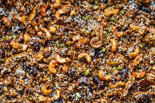 Crispy homemade granola with nuts, dried fruits and sesame seeds background.