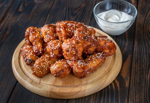 Crispy orange glazed chicken wings with blue cheese sauce on the wooden board