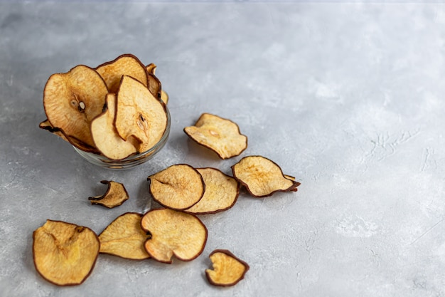 Crispy pear fruit chips on a gray table. In the table are ripe pears. Healthy food, decor.