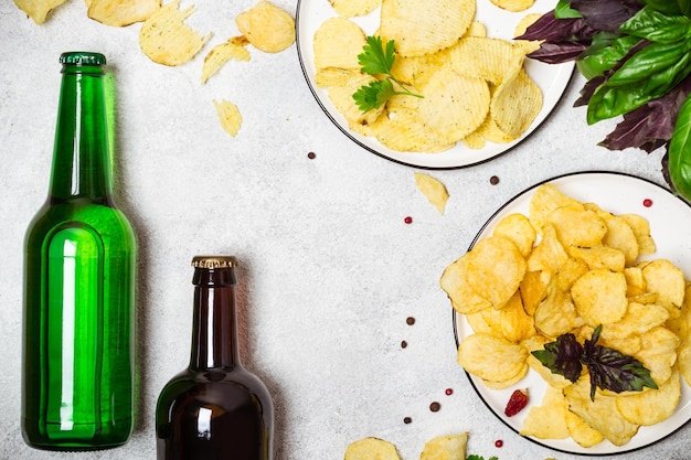 Crispy potato chips and and beer bottles on a gray background