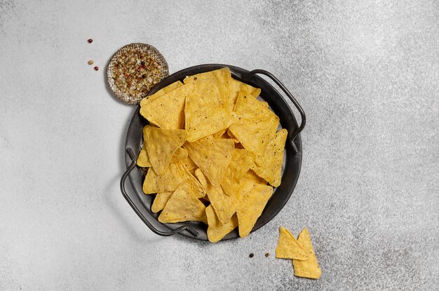 Photo crispy potato chips on a black aged plate on a table under concrete horizontal arrangement top view