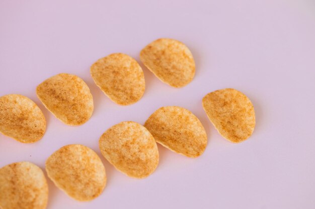 Crispy potato chips snack on pink background Fast food