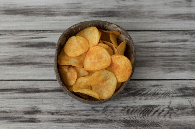 Crispy Potato Chips in a Wicker Bowl on Old Kitchen Table