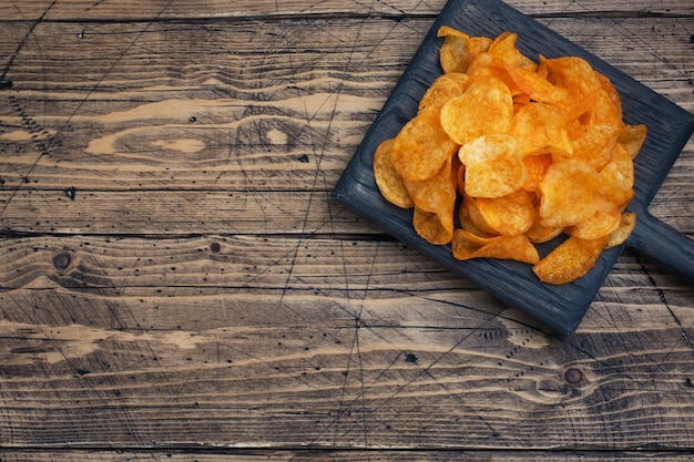 Crispy potato chips wooden background texture of golden chips Fast food snack Copy space