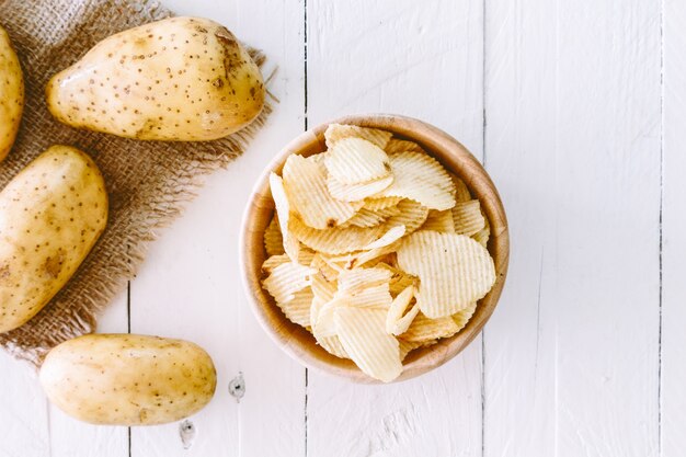 Crispy potato chips in a wooden bowl on wooden table 