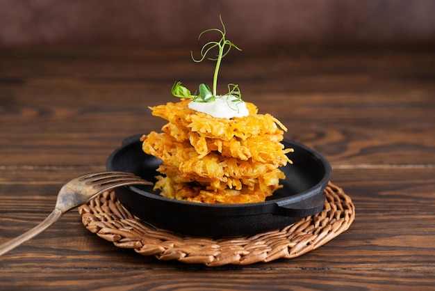 Crispy potato pancakes draniki Latkes Levivot with sour cream on stacked cast iron frying pan