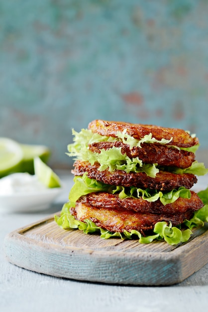 Crispy potato pancakes with green salad and yogurt sauce. Stack of potato fritters