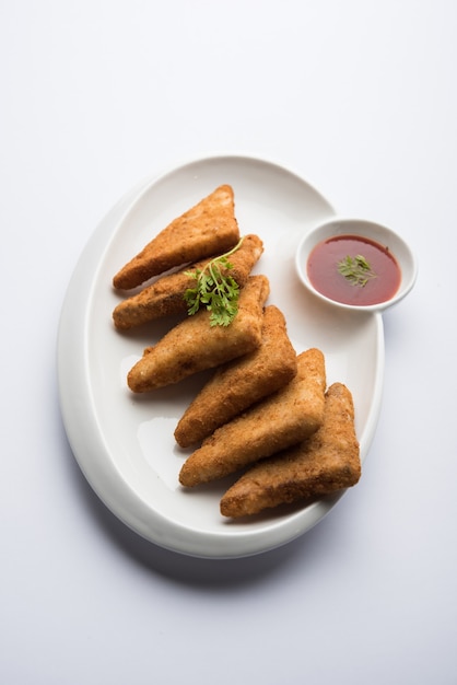 Crispy Potato triangles or batata vada covered with bread crumbs and then deep fried. served with tomato ketchup. selective focus