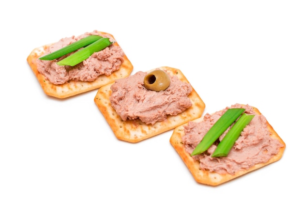 Crispy salted crackers with liver pate green onions and olives isolated