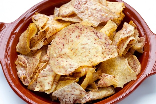 Crispy taro chips in bowl on white background