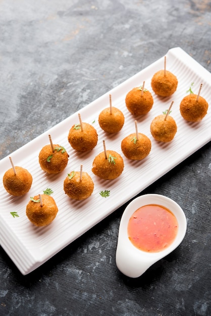 Crispy Veg lolly recept gemaakt met gekookte aardappel met kruiden bedekt met maizena en paneermeel en vervolgens gefrituurd, geserveerd met tandenstoker of ijsstokje