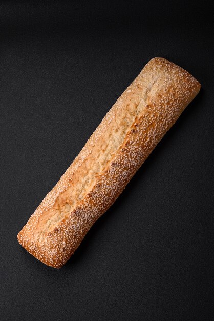 Foto baguette di farina di grano croccante con semi di sesamo su un tagliere di legno